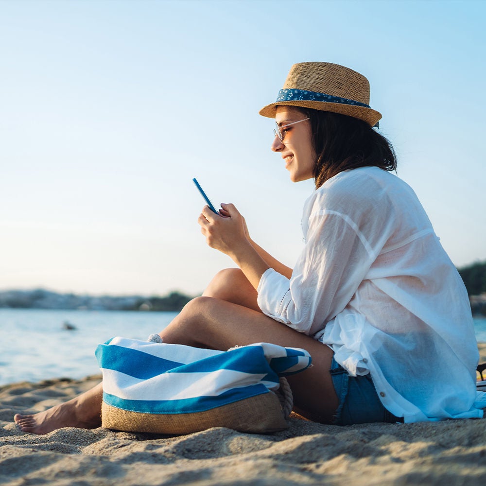 Une femme sur la plage, au téléphone.
